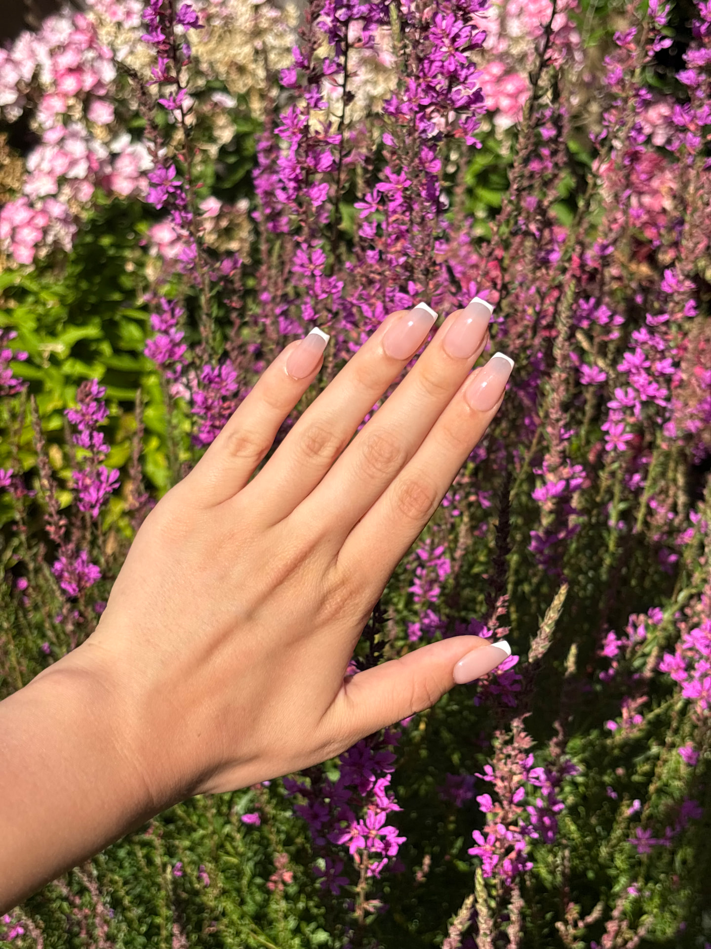 Lange nude French nagels tussen de bloemen