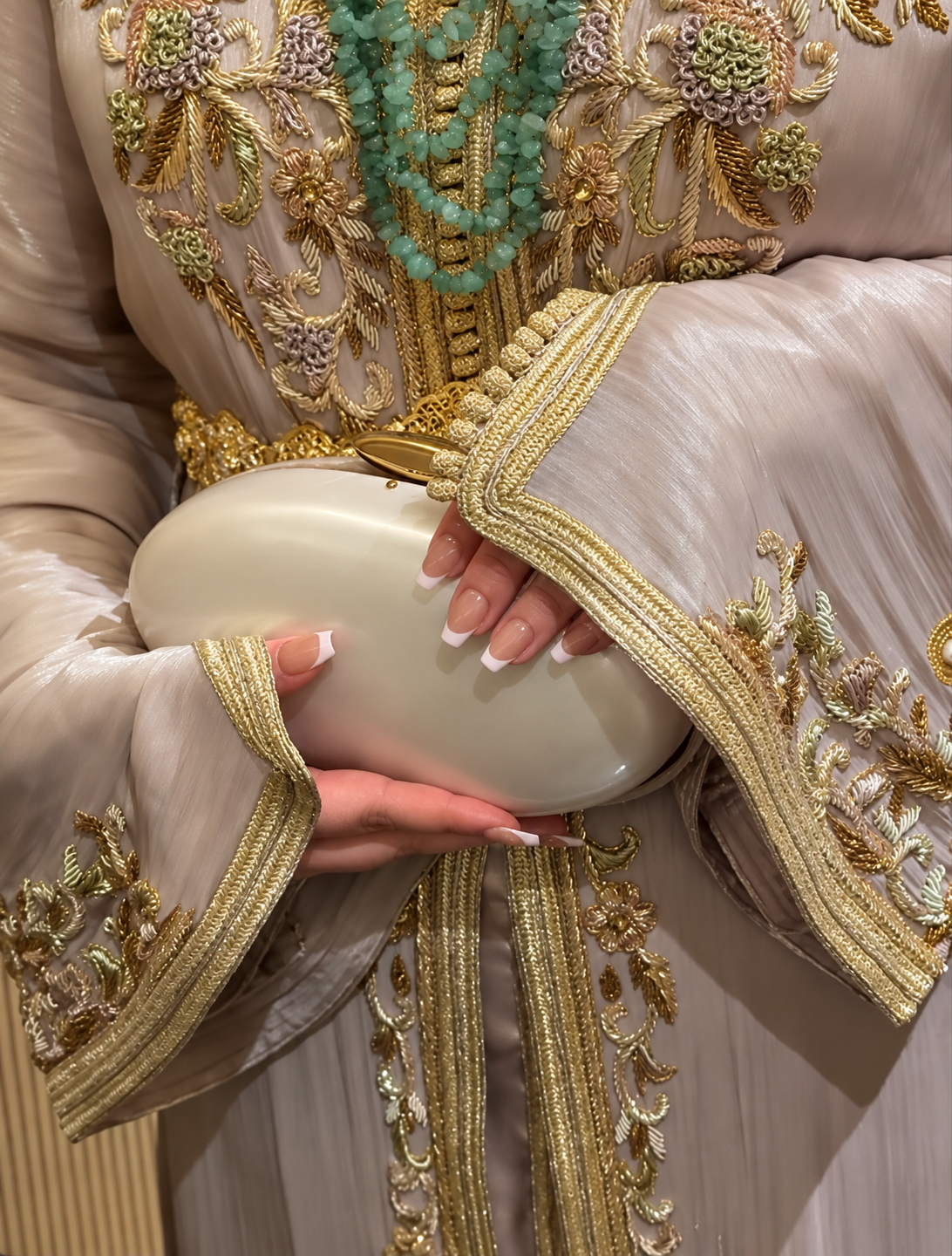 Elegante bruidslook in een goud geborduurde kaftan met klassieke French manicure